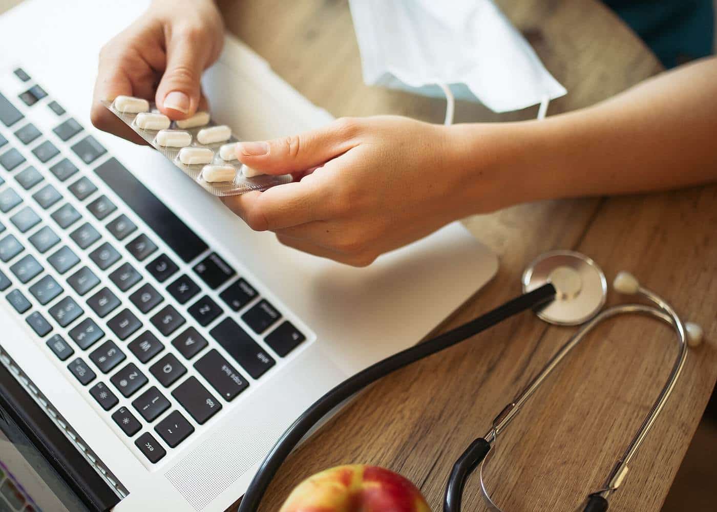 Health professional organising medication information on a laptop